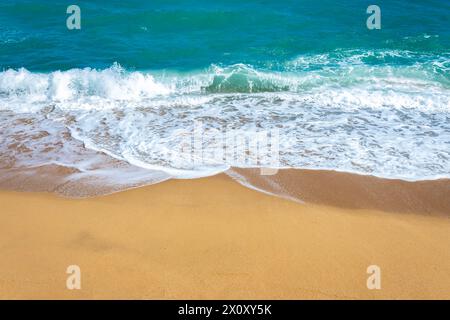 A frothy blue ocean wave on a clean sandy sea beach. Stock Photo