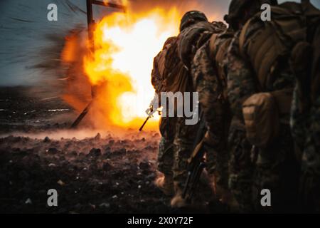 Rear view of a group of US army infantry soldiers on the battleground with an explosion in the background Stock Photo