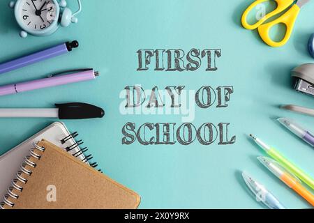 A blue background with a clock, scissors, pens, and pencils. The words first day of school are written in white Stock Photo