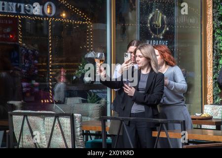 Moscow, Russia. 14th of April, 2024. Women are photographed in an outdoor cafe on a day off on Arbat pedestrian street in the center of Moscow, Stock Photo