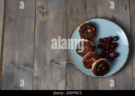 Breakfast on the table on a grey background with space for copy space text. Cottage cheese pancakes with cherries. Traditional Slavic breakfast Stock Photo