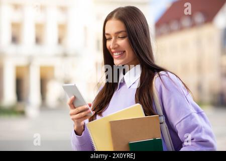 Student pretty young woman smiling at phone outdoors Stock Photo