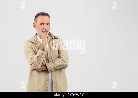 Senior man pondering with hand on chin Stock Photo