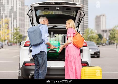 Elderly couple stowing bags in car trunk Stock Photo