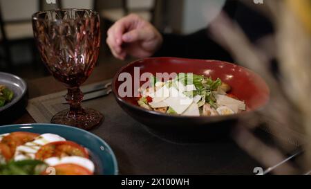 A man sits and eats a fresh vegetable salad in a gourmet restaurant. Salad in a plate in a restaurant, close-up. Stock Photo