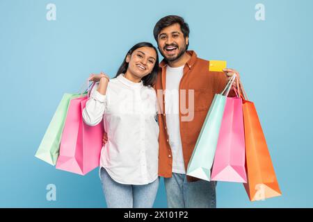 Couple with shopping bags looking joyful on blue background Stock Photo