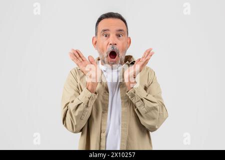 Surprised senior expressing shock with hands raised Stock Photo