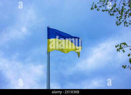 Ukrainian flag on a pole over dramatic blue sky with copy space. Flag of Ukraine on flag stock over blue sky. Stock Photo