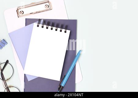 Workspace with clean notepad mock up and stationery on a blue background. School supplies. Stock Photo