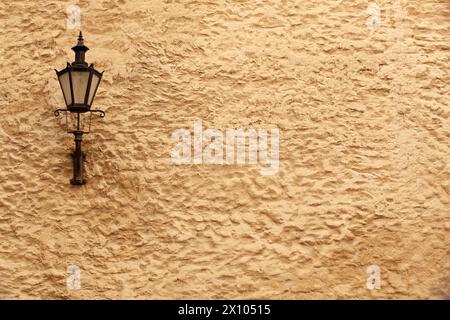 An old black lantern with glass on the yellow rough wall of a house in Tallinn. Estonia. Horizontal Stock Photo