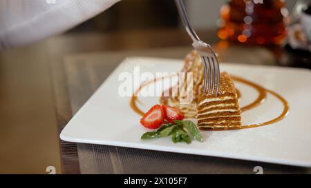 A piece of cake with icing and rke, strawberries next to it on a plate, a dish in a restaurant. Dessert in the form of a cake on a plate. Cheesecake Stock Photo