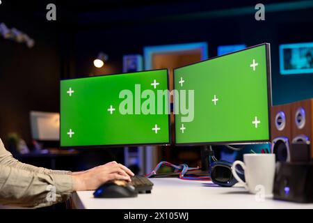 Programmer designing and developing software applications using green screen computer. IT administrator implementing and maintaining company systems using chroma key desktop PC Stock Photo