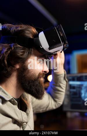 IT expert using virtual reality to make artificial intelligence become sentient, smiling after seeing self awareness signs. Man with VR glasses on happy after achieving AI superintelligence, close up Stock Photo