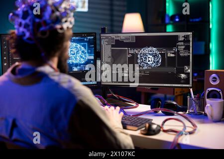 Software technician using EEG headset gear translating thoughts into PC commands using brainwave signals. IT specialist controlling computer functions using mind, helped by scifi technology Stock Photo