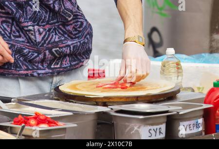The midsection body of a chef preparing sweet fruit crepes, French pancakes at farmers market stall in Prague Naplavka, Czech Republic Stock Photo