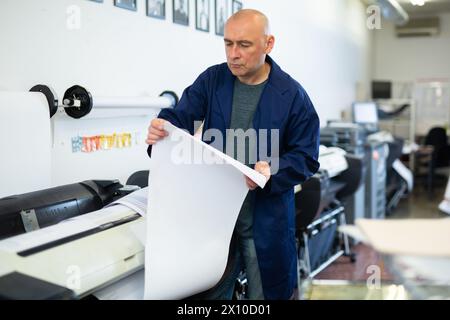 Service man uses plotter and checks functionality in printing shop Stock Photo