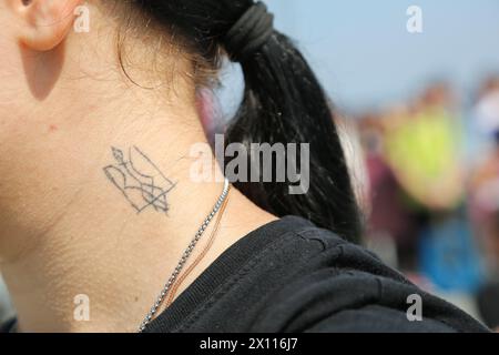 Odessa, Ukraine. 14th Apr, 2024. A tattoo of the Coat of Arms of Ukraine seen on a protester's neck during a rally on Langeron beach. A rally “Don't be silent captivity kills” was held on Lanzheron beach, the essence of which was to draw the attention of the public and authorities to prisoners who are in the Russian Federation. Credit: SOPA Images Limited/Alamy Live News Stock Photo