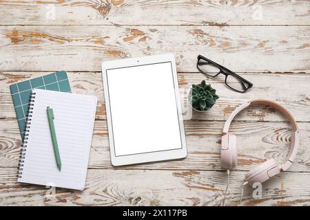 Tablet, headphones and stationery on beige wooden table Stock Photo