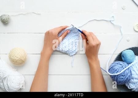 Woman knitting with yarn balls on white wooden background Stock Photo