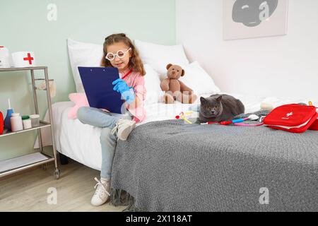 British cat visiting cute little girl doctor at home Stock Photo