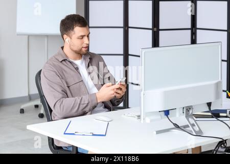 Portrait of male programmer with mobile phone working in office Stock Photo