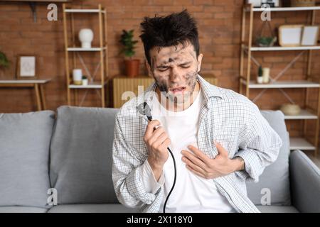 Electrocuted young man with burnt face and plug at home Stock Photo