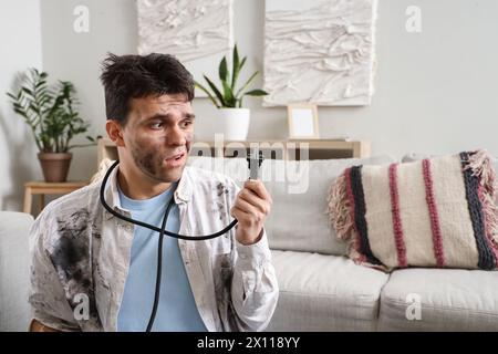 Electrocuted man with burnt face and plug at home Stock Photo