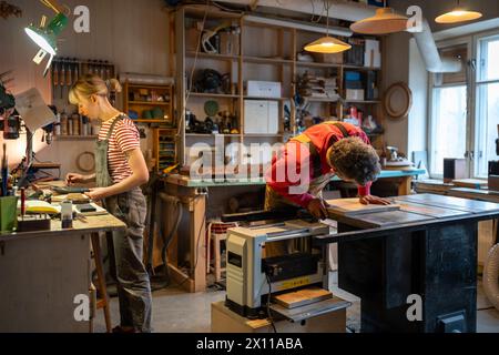 Family carpentry workshop. Busy spouses of carpenters working on wood in joinery. Stock Photo