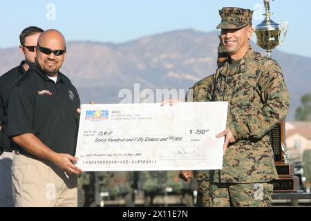 Eddie Bolanos, 46, from Oceanside, Calif., Marine Corps Community Services athletic coordinator (left), presents a first place check in Division III of the 2009 United Services Automobile Association Cup to Col. Bruce E. Nickle, commanding officer of Combat Logistics Regiment 17, 1st Marine Logistics Group (right), during a formation at Camp Pendleton, Calif., Jan. 14, 2010. Stock Photo