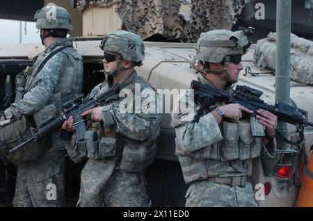 From right, Spc. Timothy Robinson, a native of Blackshear, Ga., and 1st Lt. James Gallagher, platoon leader and native of Royal Oak, Mich., both with 2nd Platoon, 1st Battalion, 64th Armor Regiment, attached to the 2nd Brigade Combat Team, 101st Airborne Division (Air Assault), pull security while Iraqi national policemen place concertina wire near a bridge in Kahdra ca. 2004 Stock Photo