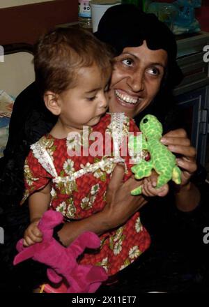 A woman with her child in the Baghdad Childrens Hospital splits a wide smile as she receives a toy from the soldiers of the 478th Civil Affairs Battalion. ca. June 27, 2004 Stock Photo