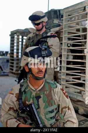 Pfc. Husam Razaq Almusowi (front) and Capt. Matthew Lillibridge exit a Stryker vehicle after returning from a mission where Almusowi translated Lillibridge's conversation to Iraqi Civil Defense Corps soldiers. Almusowi and Lillibridge are Soldiers with the 5th Battalion, 20th Infantry Regiment, 3rd Brigade, 2nd Infantry Division (Stryker Brigade Combat Team) ca. May 29, 2004 Stock Photo