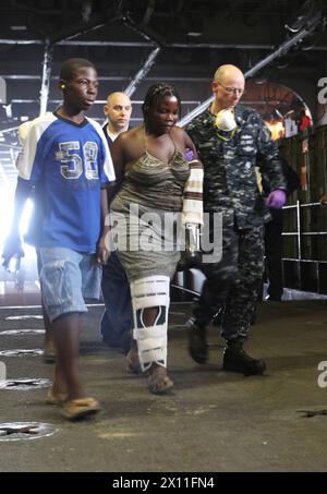 A sailor assists a Haitian woman during a casualty evacuation aboard Amphibious Assault Ship USS Bataan, Jan. 26, 2010.  Marines from 22nd Marine Expeditionary Unit and sailors from USS Bataan have assisted the Haitian people with food, water, relief supplies and medical care since their arrival, Jan. 19. Stock Photo