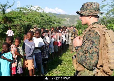 A Marine from Battalion Landing Team, 3rd Battalion, 2nd Marine Regiment, 22nd Marine Expeditionary Unit, helps guide a line for internally displaced Haitians to pick up relief supplies, Jan. 21, 2010, near Cotes de Fer, Haiti. Marines and sailors from the 22nd MEU set up a temporary relief-supply distribution point near Cotes de Fer, Haiti, bringing in bottled water and food for internally displaced Haitians. Stock Photo