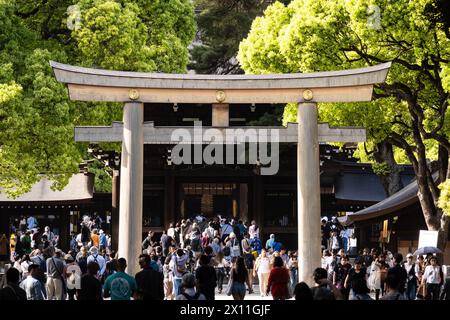 Tokyo, Japan - May 05 2023: People walk through the Tori traditional gate toward the famous Meiji Jingu Shinto temple in the heart of Tokyo between Sh Stock Photo