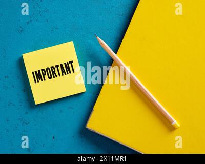 Important message on yellow sticky note paper with a pencil and binder. Stock Photo