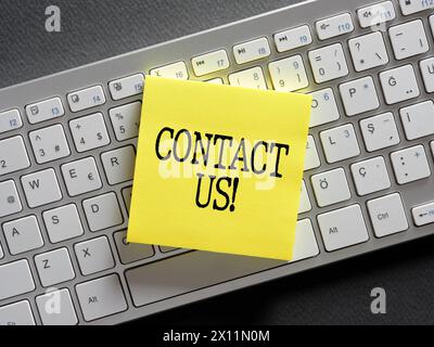 The word contact us written on a sticky note paper on computer keyboard. Business concept. Stock Photo