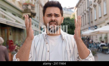 Unhappy young Caucasian man holding head business problem trouble city outdoors street frown disappointed dissatisfied guy failure loss angry upset Stock Photo