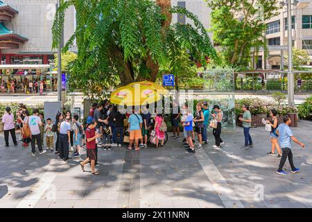 People gather around an Ice cream cart along Orchard Road in Singapore Stock Photo
