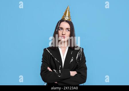 Sad woman in party hat on light blue background Stock Photo