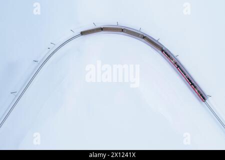 Aerial view of the famous Bernina Express passing through at Bernina pass in winter. Graubunden, Engadin, Switzerland. Stock Photo