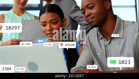 Composite of notification icons with changing numbers over diverse colleagues discussing over laptop Stock Photo