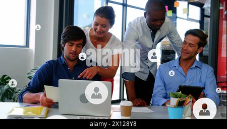 Image of profile icons over diverse coworkers discussing reports on laptop and digital tablet Stock Photo