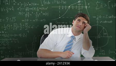 Image of Caucasian man seen waist up sitting and looking up thinking, in front of chalkboard with mo Stock Photo