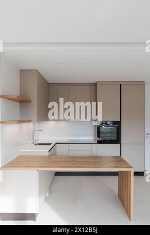 Front view of a new kitchen with a sturdy wooden table in front. Stock Photo