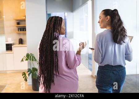 Two women are talking in a modern business office environment Stock Photo