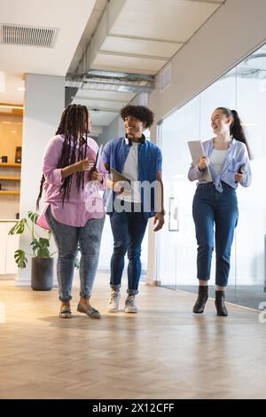 Diverse group of friends walking and talking together in a modern business office Stock Photo