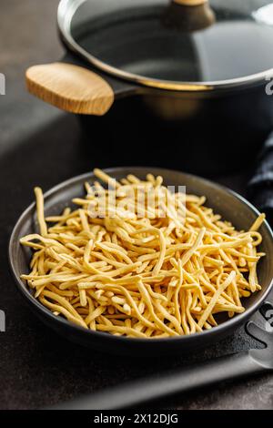 Uncooked spaetzle pasta on plate on a kitchen table. Stock Photo