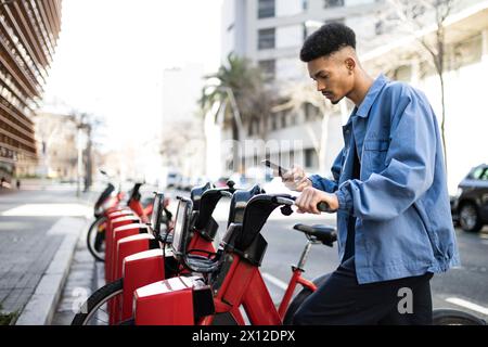 Handsome young man using bike rental digital phone app Stock Photo