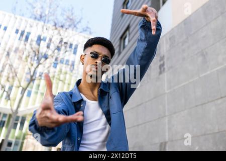 Young confident male performing gesture outside looking at camera. Stock Photo